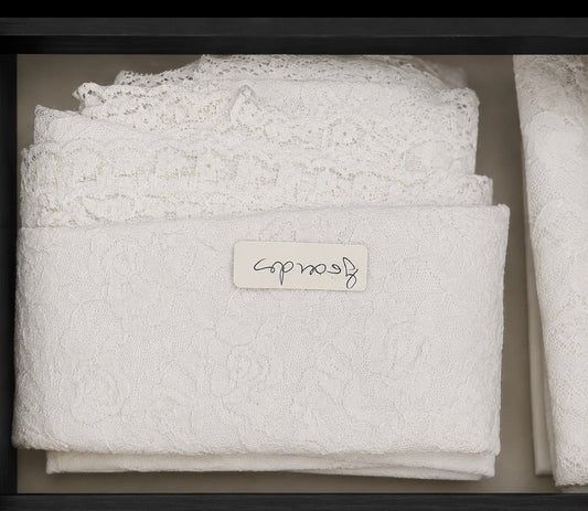Pañuelo de encaje blanco doblado, con textura floral y acabado de puntilla