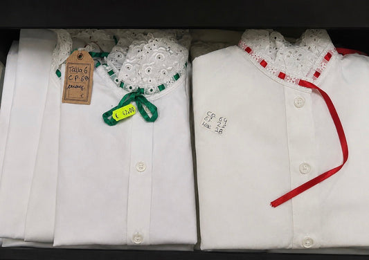 Camisas blancas con botones y cintas rojas, detalle de encaje en el cuello.