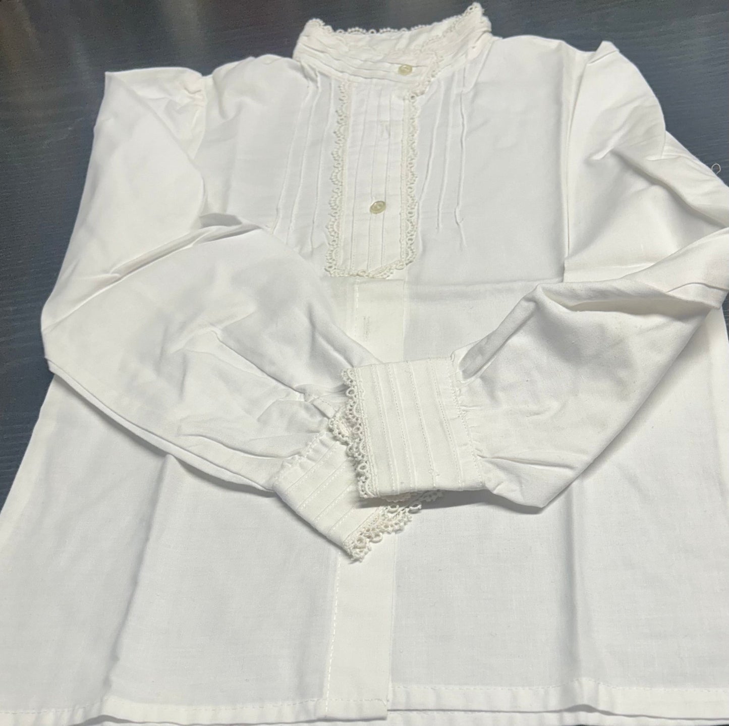 Blusa blanca de manga larga con puntilla y botones dorados al frente