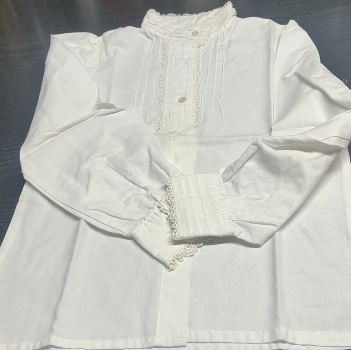 Blusa blanca de manga larga con puntilla y botones dorados al frente