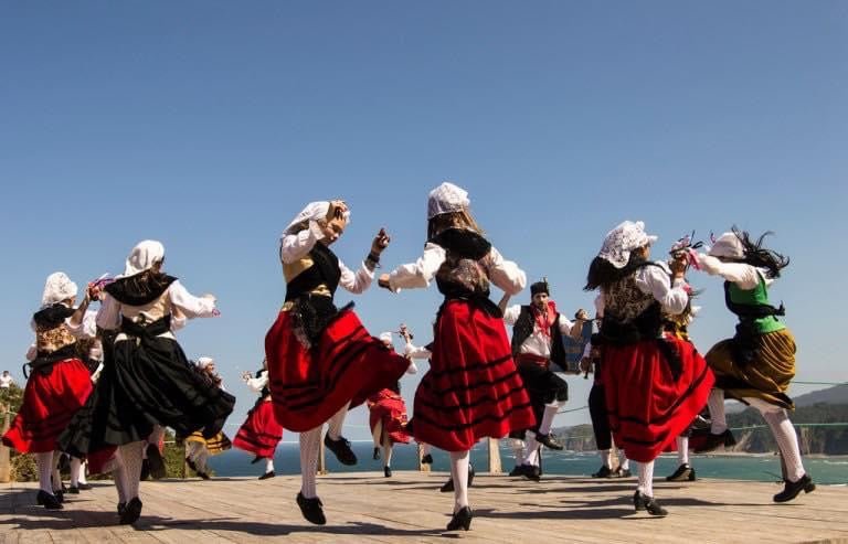 Grupo con trajes regionales: vestidos rojos y negros con sombreros