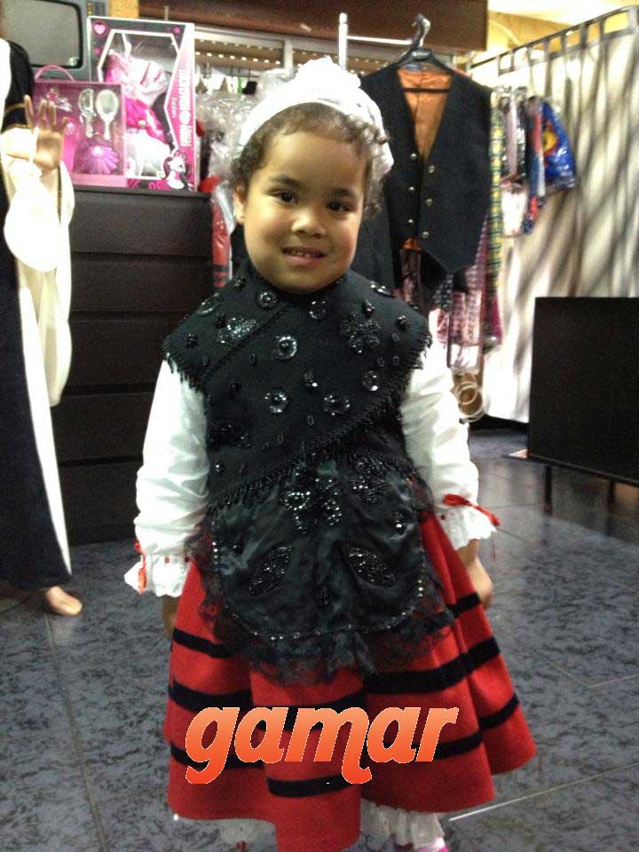 Traje infantil con chaleco negro, blusa blanca y falda roja a rayas