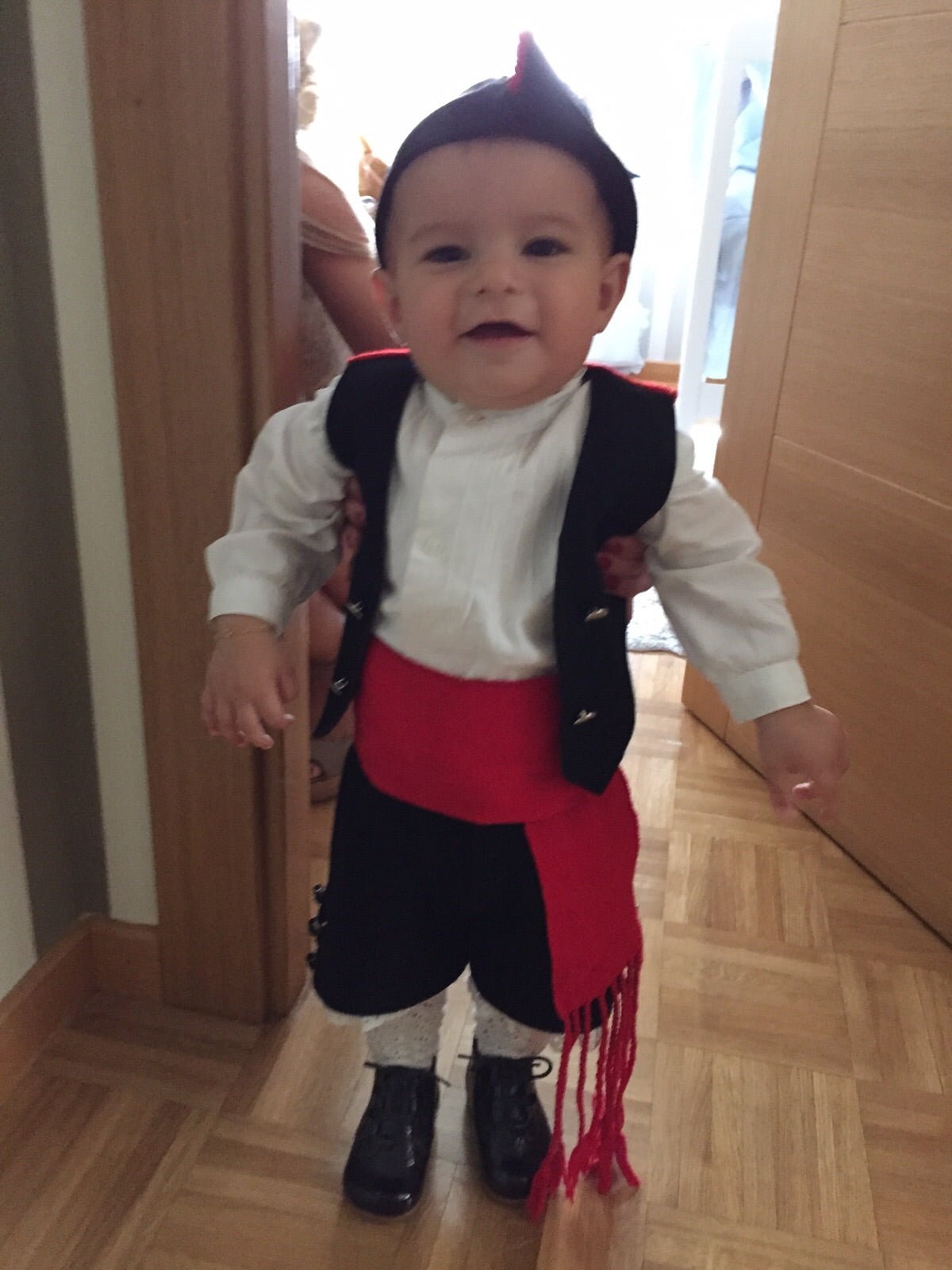 Traje regional para niño: chaleco negro, camisa blanca, pantalón oscuro, faja roja y gorro
