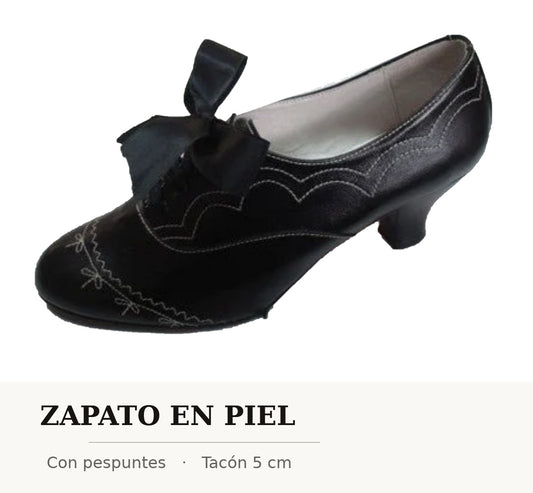 Zapato de mujer de piel negro con lazo y pespuntes, puntera redonda y tacón bajo