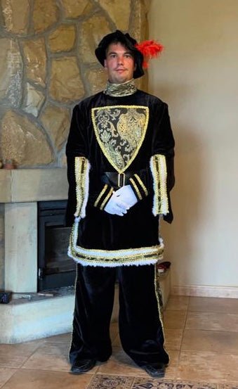 Traje de rey Gaspar: túnica negra con bordado dorado y sombrero con penacho rojo