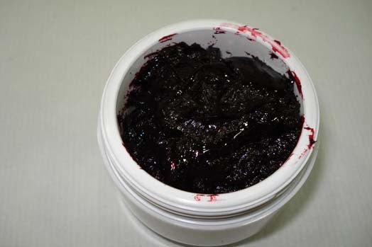 Sangre coagulada en recipiente plástico pequeño, textura oscura y densa