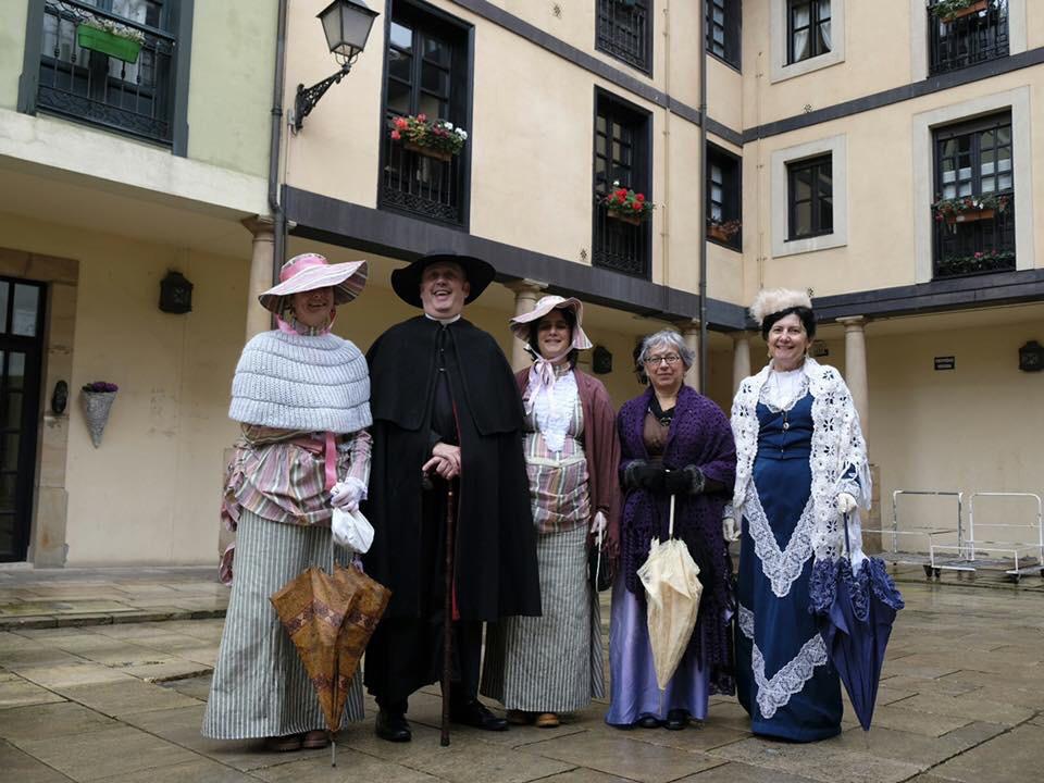 Conjunto de disfraces de época con sombreros y vestidos, varias personas.