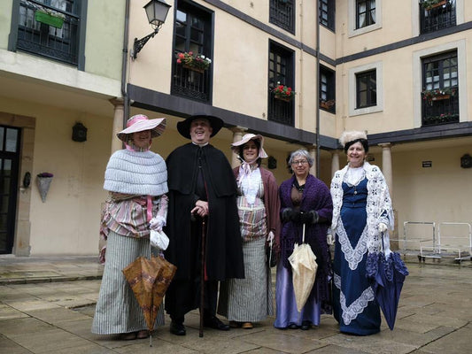 Conjunto de disfraces de época con sombreros y vestidos, varias personas.