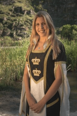 Vestido medieval con corpiño negro, delantal blanco y bordado dorado con coronas.