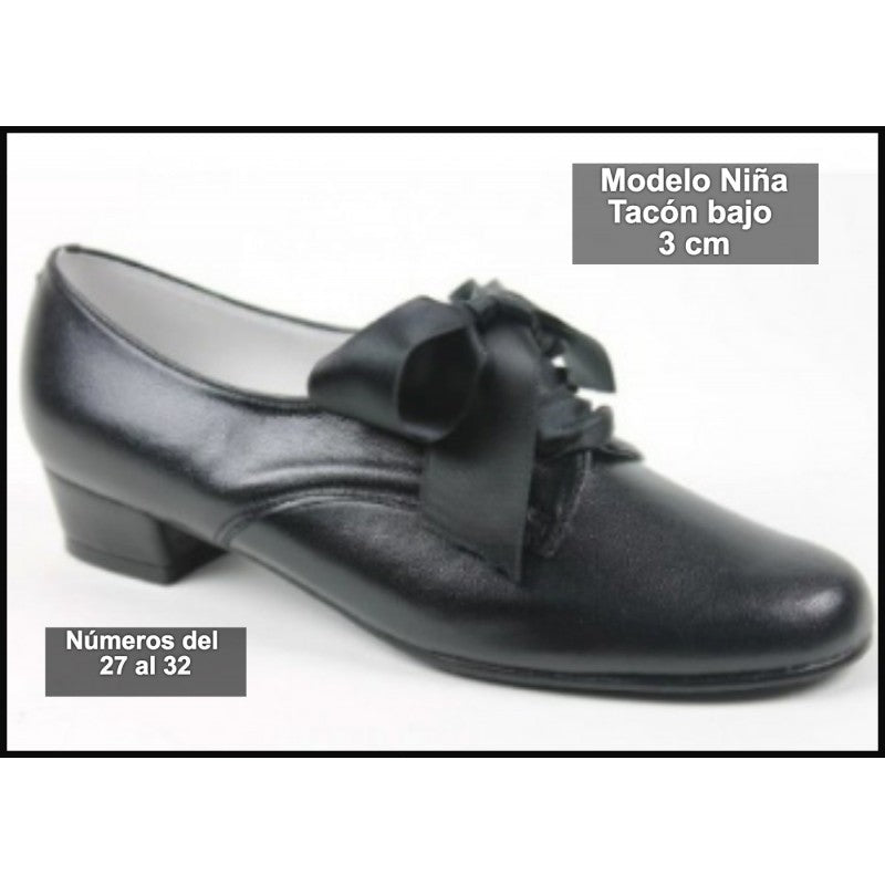 Zapato infantil de piel con moño en la empeine y tacón bajo, color oscuro.