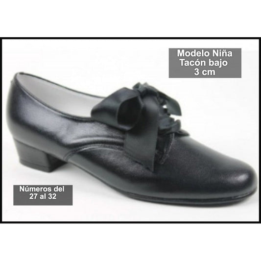 Zapato infantil de piel con moño en la empeine y tacón bajo, color oscuro.
